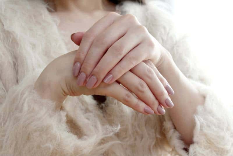 부드러운 니트 옷을 입은 사람이 두 손을 겹쳐 올리고 있는 모습으로, 손가락과 손등이 살짝 부어 보이는 상태를 표현한 이미지.