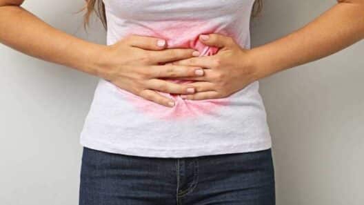 복부 중앙을 손으로 감싸며 통증이나 압박감을 느끼는 모습으로, 생리 전 호르몬 변화로 인한 붓기와 불편함을 시각적으로 표현한 이미지.