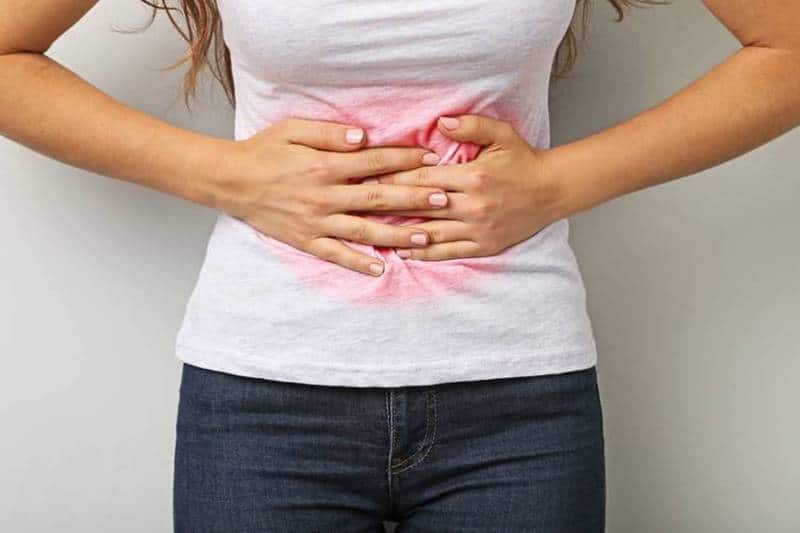 복부 중앙을 손으로 감싸며 통증이나 압박감을 느끼는 모습으로, 생리 전 호르몬 변화로 인한 붓기와 불편함을 시각적으로 표현한 이미지.